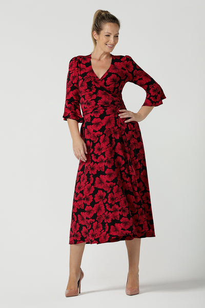 A size 10 woman wearing the size 10 Portia dress in Bold Poppy. Made in Australia for women size 8 - 24. A functioning wrap dress with waist ties and flutter sleeves.