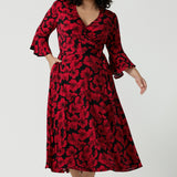 Size 18 woman wears the Portia dress in Bold Poppy. Red floral dress with flutter sleeves and a black base. Made in Australia for women size 8 - 24. 