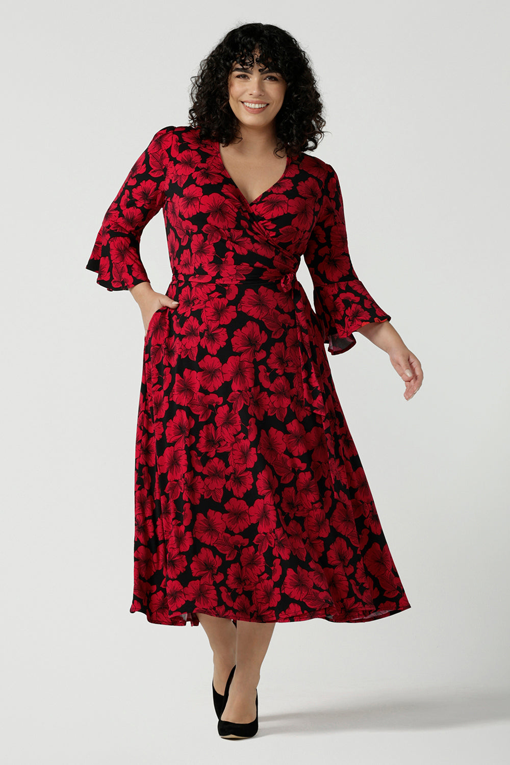 Size 18 woman wears the Portia dress in Bold Poppy. Red floral dress with flutter sleeves and a black base. Made in Australia for women size 8 - 24. 