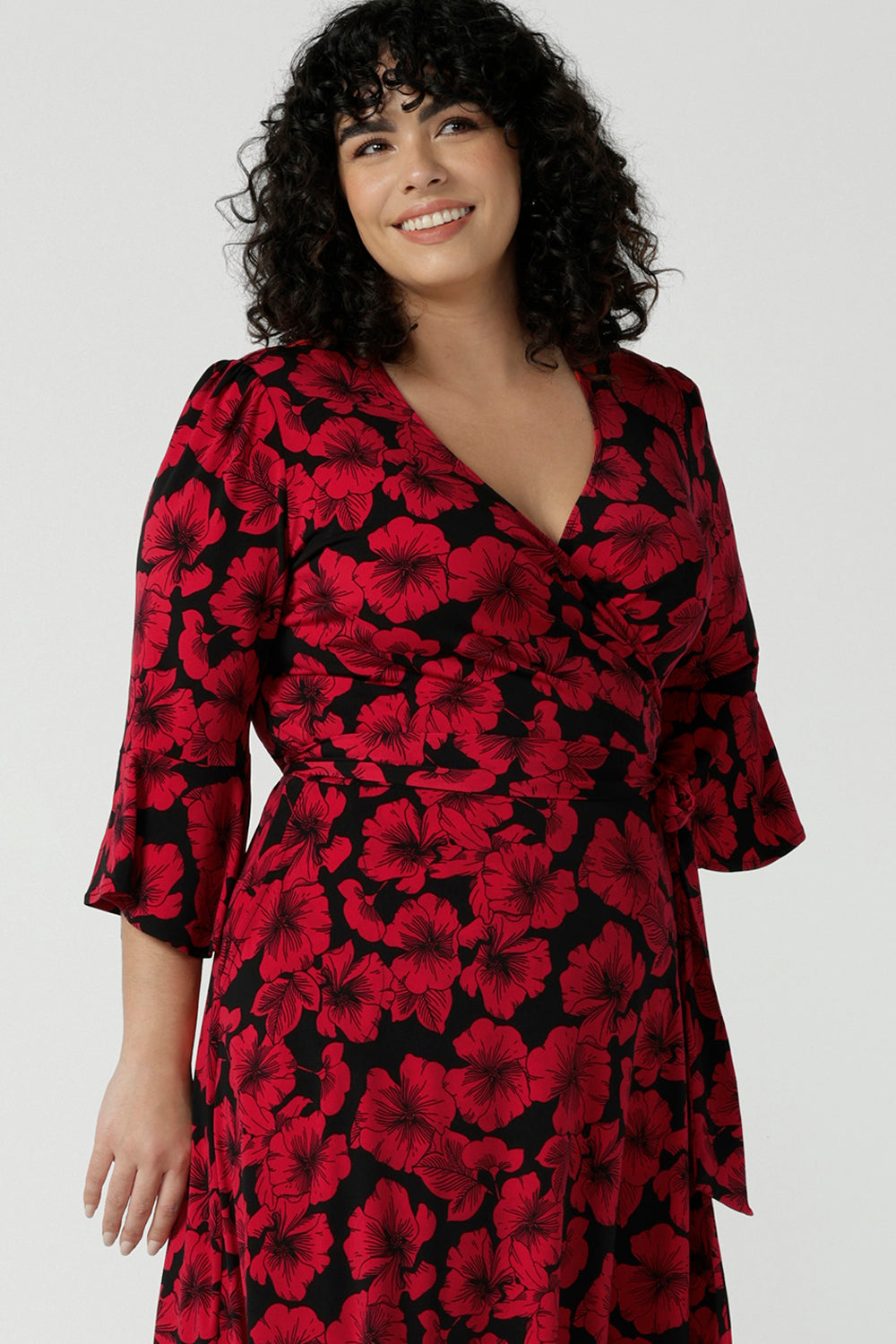 Close up of a size 18 woman wears the Portia dress in Bold Poppy. Red floral dress with flutter sleeves and a black base. Made in Australia for women size 8 - 24.