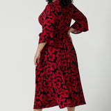 Back view of a size 18 woman wears the Portia dress in Bold Poppy. Red floral dress with flutter sleeves and a black base. Made in Australia for women size 8 - 24.