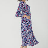 Featuring a soft wrap neckline, fluted 3/4 sleeves with gathered detail, and pockets, it’s designed with comfort, elegance and movement in mind.