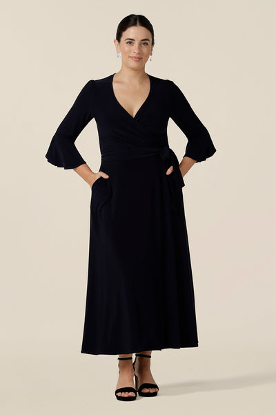 Shown for petite height women, this navy blue wrap dress is perfect for elegant evening and occasion wear. This is a smart casual dress with 3/4, fluted sleeves and a full midi-length skirt. Made in Australia, shop wrap dresses in sizes 8 to 24 at Leina & Fleur.