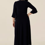 Back view of a classic navy blue wrap dress, for petite height women. Perfect for elegant evening and occasion wear, this is a cocktail dress with 3/4 sleeves and a full midi-length skirt. Made in Australia, shop wrap dresses in sizes 8 to 24 at Leina & Fleur.