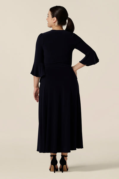 Back view of a classic navy blue wrap dress, for petite height women. Perfect for elegant evening and occasion wear, this is a cocktail dress with 3/4 sleeves and a full midi-length skirt. Made in Australia, shop wrap dresses in sizes 8 to 24 at Leina & Fleur.