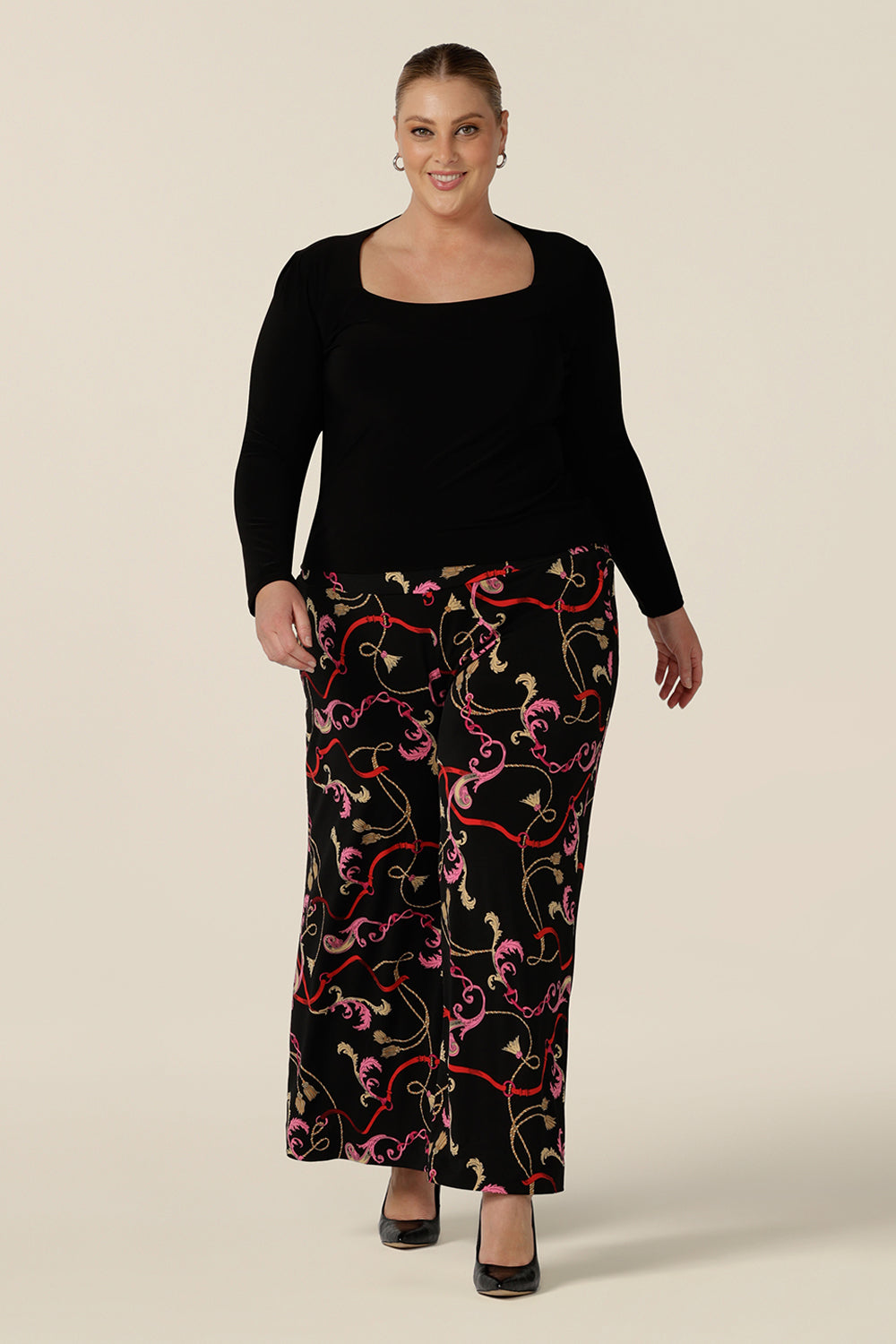 A fuller figure, size 18 woman wears printed wide leg pants with pockets and square neck, long sleeve black top as a work outfit. These pull-on, easy care pants are comfortable for your everyday workwear capsule wardrobe. Shop these Australian-made wide leg trousers online in sizes 8 to 24, petite to plus sizes.