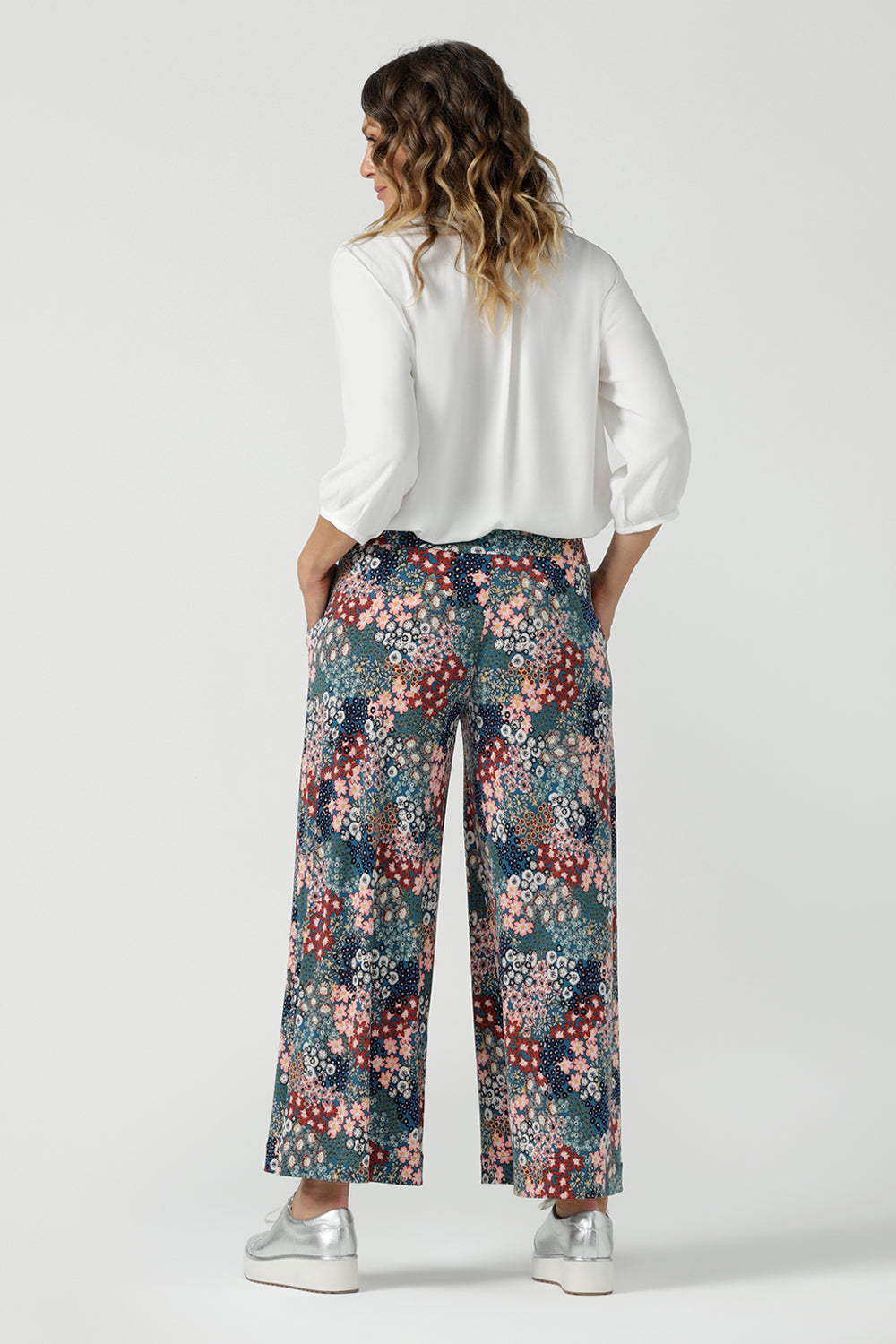 Close up of a size 10 woman wears the Presley Pant in Whimsy, a wide leg pant with a Whimsy print. A made in Australia wide leg pant with a ditsy floral print print. Size inclusive fashion for women size 8-24. Styled back with a Arley Shirt in White Tencel.