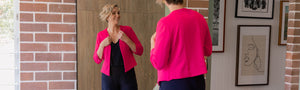Showcasing their workwear for tall and curve women, this image shows a tall woman wearing a watermelon pink jacket over a wide leg navy blue jumpsuit both by Leina and Fleur. An Australian and New Zealand women's clothing brand, Leina & Fleur offers made-in-Australia clothing for petite to plus size women. .