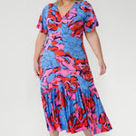 Crafted from slinky jersey, the Rio Dress in Can Can is a lightweight maxi featuring a flattering empire-line bodice, deep V-back, flared sleeves, and a gathered hem with a flowing tail effect—perfect for effortless summer elegance.