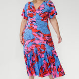 Crafted from slinky jersey, the Rio Dress in Can Can is a lightweight maxi featuring a flattering empire-line bodice, deep V-back, flared sleeves, and a gathered hem with a flowing tail effect—perfect for effortless summer elegance.