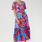 Crafted from slinky jersey, the Rio Dress in Can Can is a lightweight maxi featuring a flattering empire-line bodice, deep V-back, flared sleeves, and a gathered hem with a flowing tail effect—perfect for effortless summer elegance.