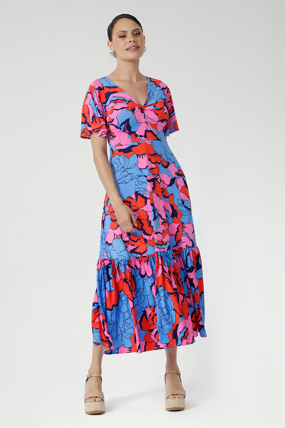 Crafted from slinky jersey, the Rio Dress in Can Can is a lightweight maxi featuring a flattering empire-line bodice, deep V-back, flared sleeves, and a gathered hem with a flowing tail effect—perfect for effortless summer elegance.