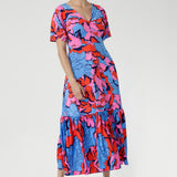 Crafted from slinky jersey, the Rio Dress in Can Can is a lightweight maxi featuring a flattering empire-line bodice, deep V-back, flared sleeves, and a gathered hem with a flowing tail effect—perfect for effortless summer elegance.