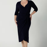 Size 12  woman wears the Robin dress in Navy. Midi length with 3/4 sleeves. V-neckline with a functioning wrap. A great work to weekend piece. Made in Australia for women size 8 - 24.