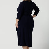 Back view of a size 18 curvy woman wears the Robin dress in Navy. Midi length with 3/4 sleeves. V-neckline with a functioning wrap. A great work to weekend piece. Made in Australia for women size 8 - 24.