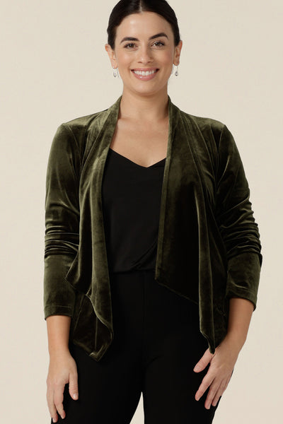 A size 10, petite height woman wears a waterfall front velour jacket for evening and cocktail wear. In bracken green this cocktail jacket is good for evening, occasion and wedding guest outfits. Shop made-in-Australian occasionwear in petite to plus sizes at Leina & Fleur.