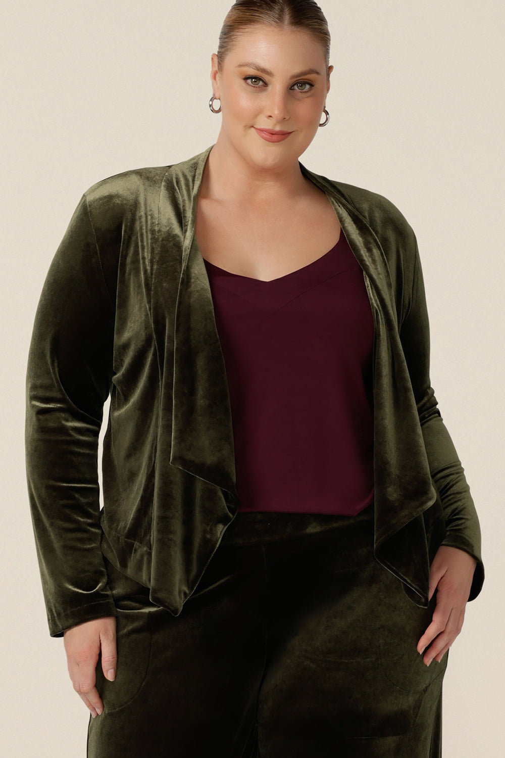 A size 18, plus size woman wears a waterfall front velour jacket for curve evening and cocktail wear. In bracken green this cocktail jacket is good for evening, occasion and wedding guest outfits. Shop made-in-Australian occasionwear in petite to plus sizes at Leina & Fleur.