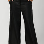 Woman's linen pants are showcased on size 12 woman styled with clay coloured cami & black high heels. This high-rise pant features a functioning waistband with a fly fastening and hook-and-bar closure, complemented by belt loops for added versatility.