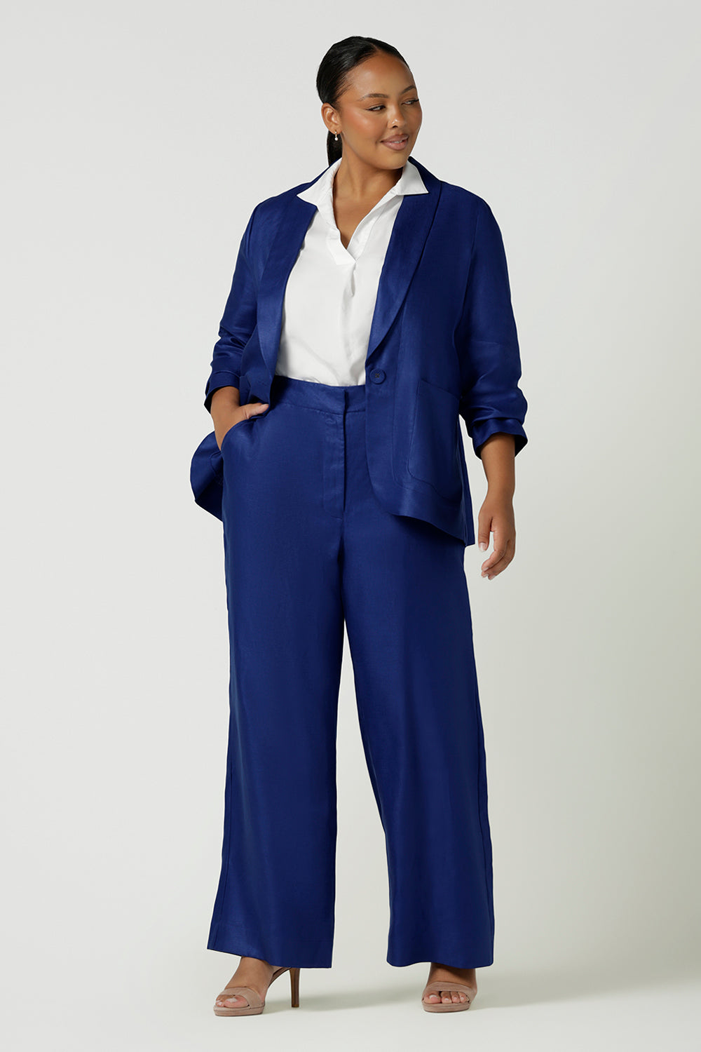 A size 12 woman wears the Ronnie Pant in Cobalt Linen. A high waist soft tailored pant with a fly front and belt loops. Styled back with the Houston Blazer in cobalt linen. Made in Australia for women size 8 - 24.