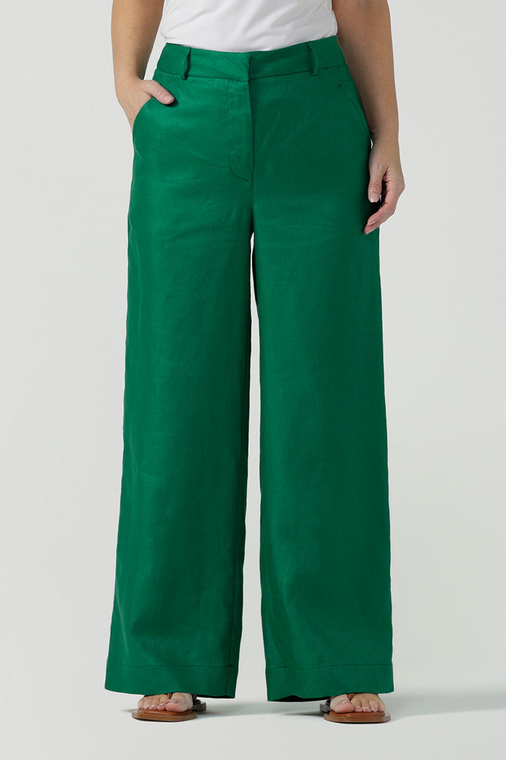 A size 12 woman wears a tailored linen pant in 100% linen. Breathable linen fabrication in a beautiful emerald green colour. The perfect workwear pants with pockets that make great summer pants. Size inclusive fashion designed and made in Australia size 8 - 24. 