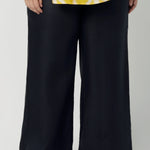 Close up image of size 18 curvy woman wears a tailored linen pants in 100% linen. Breathable linen fabrication in striking deep midnight navy colour. The perfect workwear pants with pockets that make great summer pants. Size inclusive fashion designed and made in Australia size 8 - 24. 