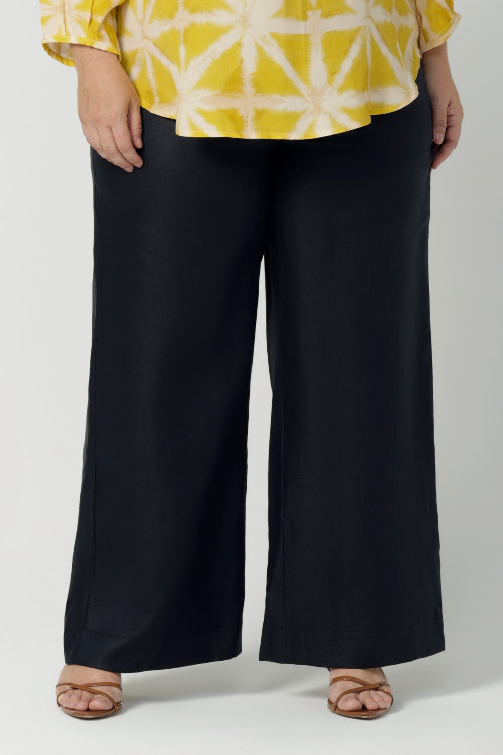 Close up image of size 18 curvy woman wears a tailored linen pants in 100% linen. Breathable linen fabrication in striking deep midnight navy colour. The perfect workwear pants with pockets that make great summer pants. Size inclusive fashion designed and made in Australia size 8 - 24. 