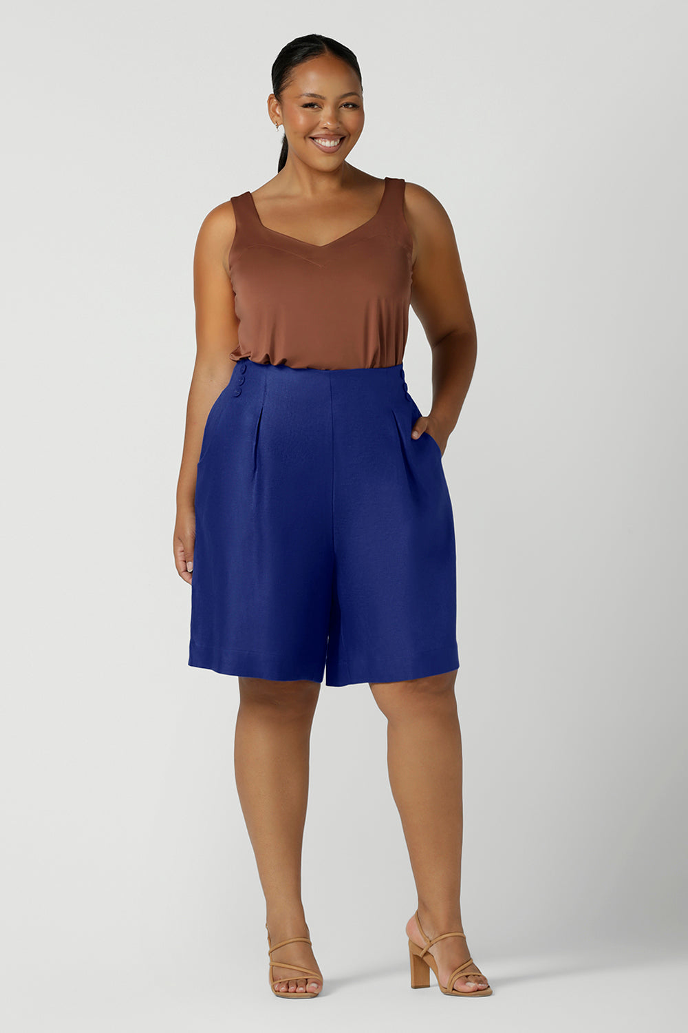 Size 16 woman wears Cobalt Linen Bermuda short  in Cobalt. High waist short with pleat front and self cover buttons. Bermuda short length. Made in Australia for women size 8 - 24.