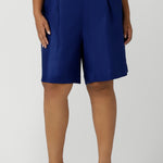 Close up of a size 16 woman wears Cobalt Linen Bermuda short in Cobalt. High waist short with pleat front and self cover buttons. Bermuda short length. Made in Australia for women size 8 - 24.