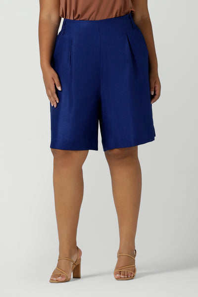 Close up of a size 16 woman wears Cobalt Linen Bermuda short in Cobalt. High waist short with pleat front and self cover buttons. Bermuda short length. Made in Australia for women size 8 - 24.