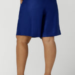 Back view of a size 16 woman wears Cobalt Linen Bermuda short in Cobalt. High waist short with pleat front and self cover buttons. Bermuda short length. Made in Australia for women size 8 - 24.