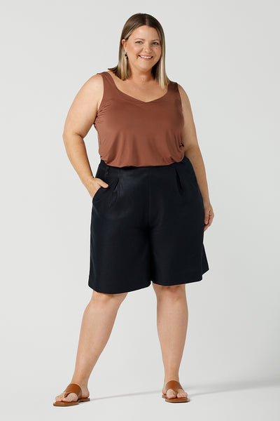 A curvy size 18 woman wears 100% Linen Bermuda shorts. The perfect smart casual shorts suitable for summer workwear to take you through to the weekend. Beautiful midnight navy colour and soft tailoring details. Designed and made in Australia for sizes 8 -24.
