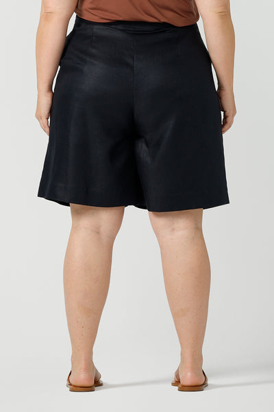 Back view of a curvy size 18 woman wears 100% Linen Bermuda shorts. The perfect smart casual shorts suitable for summer workwear to take you through to the weekend. Beautiful midnight navy colour and soft tailoring details. Designed and made in Australia for sizes 8 -24.