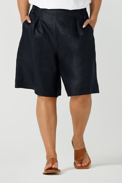 Close up of a curvy size 12 woman wears 100% Linen Bermuda shorts. The perfect smart casual shorts suitable for summer workwear to take you through to the weekend. Beautiful midnight navy colour and soft tailoring details. Designed and made in Australia for sizes 8 -24.