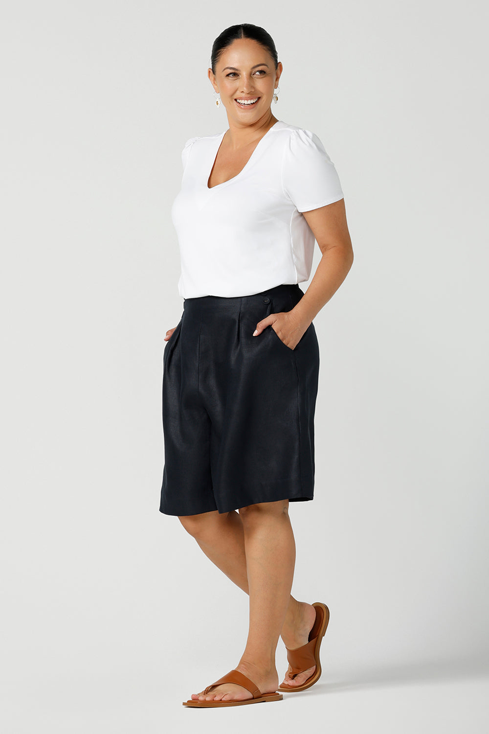 Close up of a curvy size 12 woman wears 100% Linen Bermuda shorts. The perfect smart casual shorts suitable for summer workwear to take you through to the weekend. Beautiful midnight navy colour and soft tailoring details. Designed and made in Australia for sizes 8 -24.