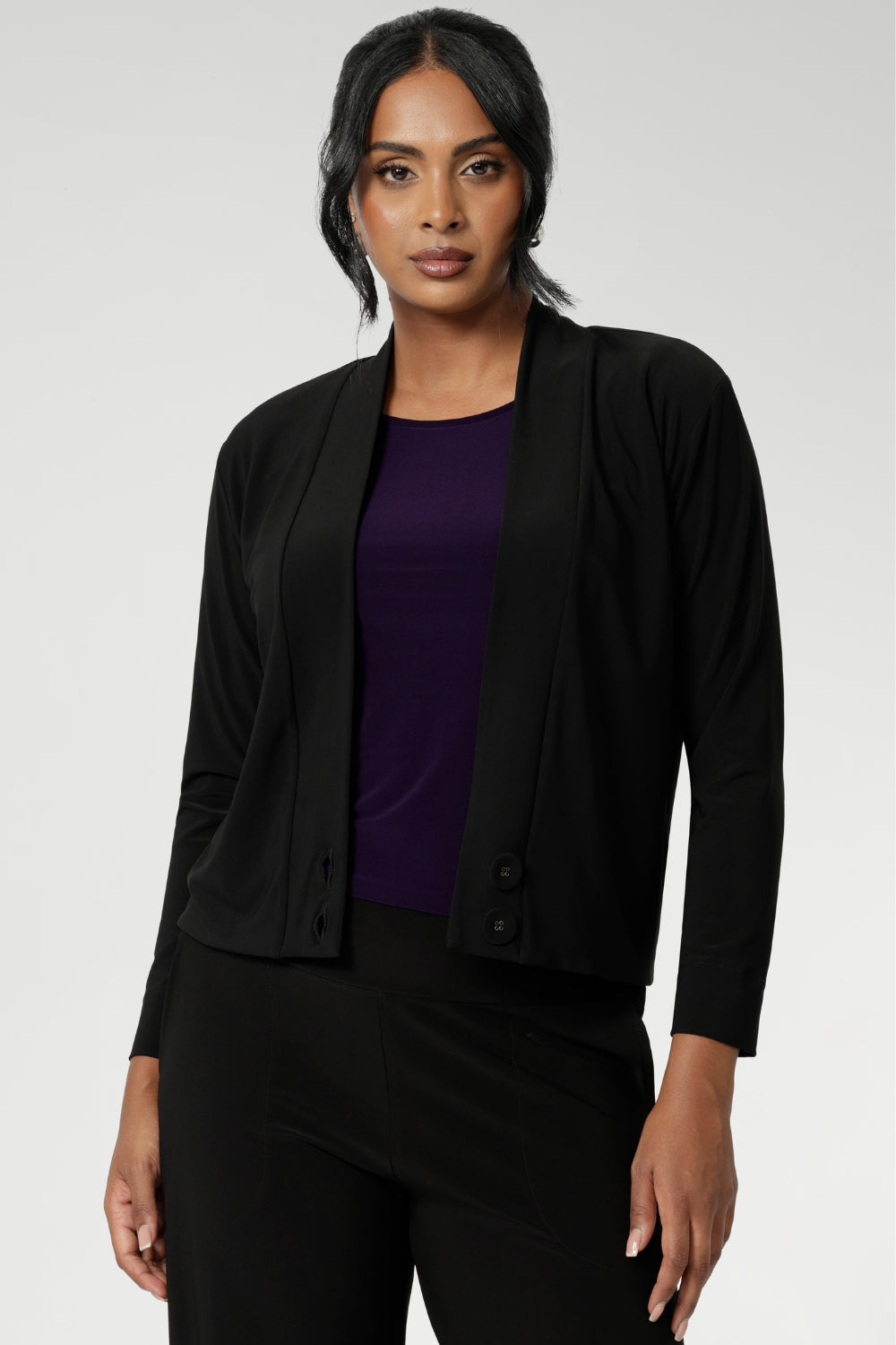 Over 30's woman wears a black V-neck jacardi with long sleeves. Designed to help women in Australia and New Zealand transition for cool weather. This jacket/cardigan is a transeasonal cover-up made from stretchy jersey fabric. Shop this jacket-cardigan hybrid in sizes 8-24.