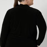 Back view of size 18 woman wears black, part jacket, part cardigan. Soft jacket is a transeasonal cover up, perfect for workwear layering. Featuring a V-neckline, long sleeves and buttons. This casual black jacket is made in stretch jersey for comfortability through the seasons. Available in sizes 8-24.