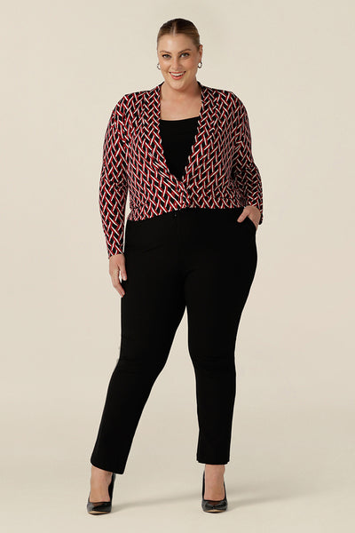 A plus size woman wears a soft jacket/cardigan with long sleeves and covered button fastenings.  An easy throw on jacket for work, office and casual wear, this jacket is worn with a black jersey top and slim leg black work pants. Shop now in petite to plus sizes.