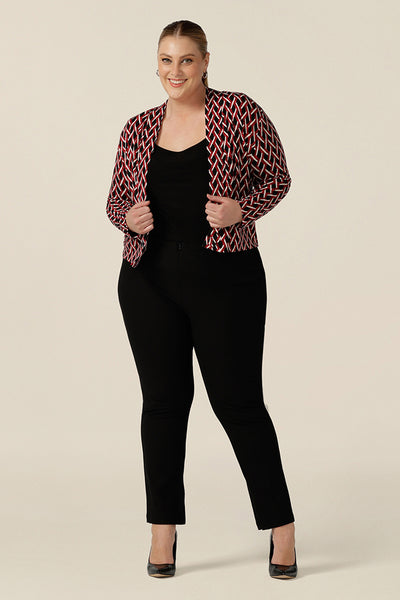 A plus size woman wears a soft jacket/cardigan with long sleeves and covered button fastenings. An easy throw on jacket for work, office and casual wear, this jacket is shown worn open with a black jersey top and slim leg black work pants. Shop now in petite to plus sizes.