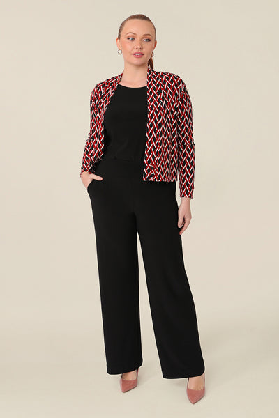 A curvy woman wears a soft jacket/cardigan with long sleeves and covered button fastenings. Styled open, this women's jacket is worn with a black top and wide leg black work pants. An easy throw on jacket for work, office and casual wear, shop made-in-Australia workwear petite to plus sizes