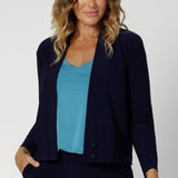 Size 12 woman wears navy jacket/cardigan. Featuring long sleeves, this jacket-cardigan hybrid is the perfect trans-seasonal cover up for women. Move into the cooler months in style, with this comfortable jacket for workwear and casual layering. Available in sizes 8-24.