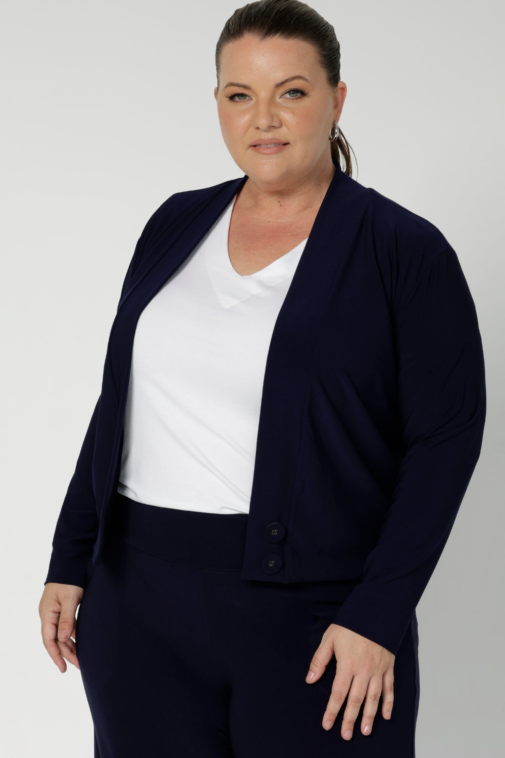 Size 18 curvy woman wears a jersey jacket/cardigan style in navy. With long sleeves, this jacket-cardigan hybrid is cool weather cover up for women. Easily transition into cooler months in style, with this comfortable jacket for workwear and casual layering. Available in sizes 8-24.