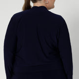 Size 18 woman wears a long sleeve jacket-cardigan hybrid in navy colour. Comfortable workwear jacket is made fro easing into the cooler months. Australian made from dry touch jersey fabric. Model wears Jacardi paired with white top and navy work pants to curate an easy back to work look.