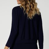 Back view image of long sleeved jacket-cardigan hybrid worn by over 40's woman. The perfect trans-seasonal cover up for women for the cooler months or for comfort in cold office spaces. Comfortable jacket provides elevated workwear styling, paired back with matching pants or over dresses. Available in sizes 8-24.