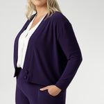 The Sandro Jacardi in Purple is crafted from a heavy-weight, dry-touch jersey base with a soft stretch that moves with you throughout the day, offering both comfort and a polished appearance. Plus size women wears purple cardigan with matching pull on workwear pants.