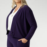 The Sandro Jacardi in Purple is crafted from a heavy-weight, dry-touch jersey base with a soft stretch that moves with you throughout the day, offering both comfort and a polished appearance. Plus size women wears purple cardigan with matching pull on workwear pants.