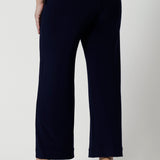 A petite height woman wears navy work pants in petite length with a jersey t-shirt in amber colour. Great pants for short women, these Australian-made pull-on trousers are available in sizes 8 to 24, petite to plus sizes.