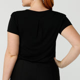 Back view of the shoulder yoke and back pleat of a women's black top. A good black top for your capsule wardrobe, this round neck, short sleeve top in black bamboo jersey is comfortable for work and casual wear. Made in Australia by ladies clothing brand, Leina & Fleur this black tee top is worn by a size 12 curvy woman. Shop black tops for women online in sizes 8 to 24 in L&F's online fashion boutique