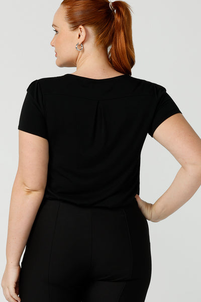 Back view of the shoulder yoke and back pleat of a women's black top. A good black top for your capsule wardrobe, this round neck, short sleeve top in black bamboo jersey is comfortable for work and casual wear. Made in Australia by ladies clothing brand, Leina & Fleur this black tee top is worn by a size 12 curvy woman. Shop black tops for women online in sizes 8 to 24 in L&F's online fashion boutique