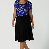 Size 16 curvy woman wears the Sawyer top a scoop neckline top on a polka dot print with a cobalt base. Styled back with a black Cassidy skirt.Made in Australia for women size 8 to 24.