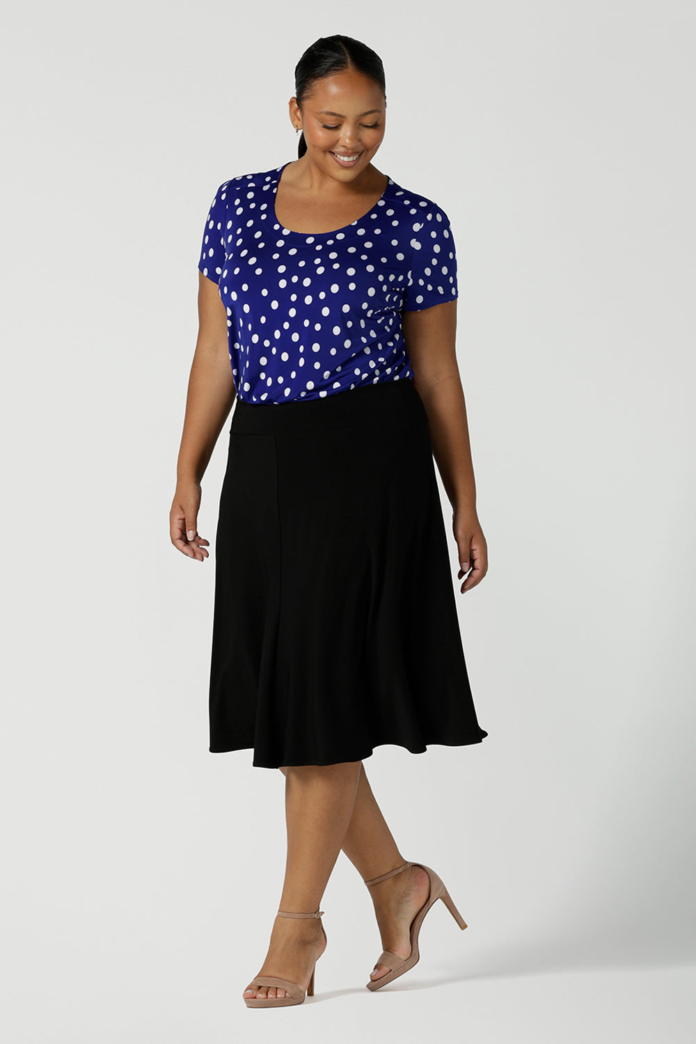 Size 16 curvy woman wears the Sawyer top a scoop neckline top on a polka dot print with a cobalt base. Styled back with a black Cassidy skirt.Made in Australia for women size 8 to 24.